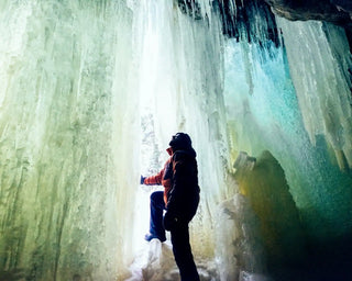 Person standing in front of a large ice formation with a backpack
